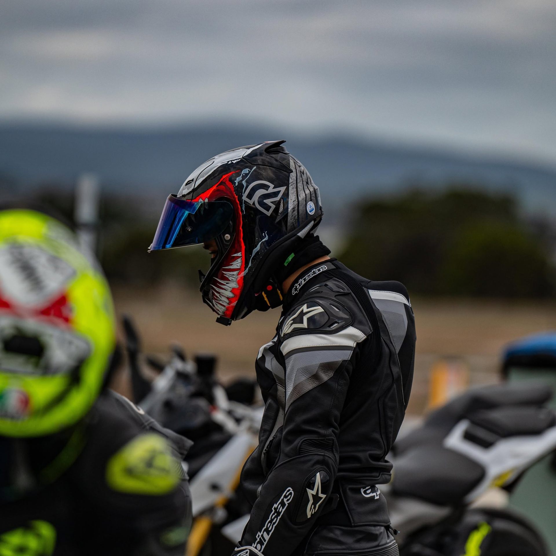 Rider in Alpinestars leathers with a graphic helmet on the grid